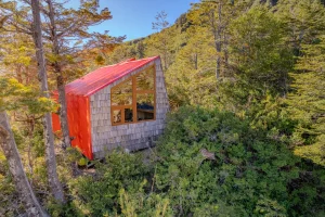 Toma de una estructura de ladrillos con techo rojo y una ventana que es parte de los refugios de montaña.