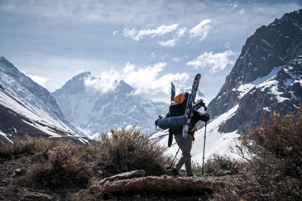 Fotografía del montañista chileno Juan Pablo Mohr usando ropa abrigadora y caminando sobre una montaña cubierta de nieve.