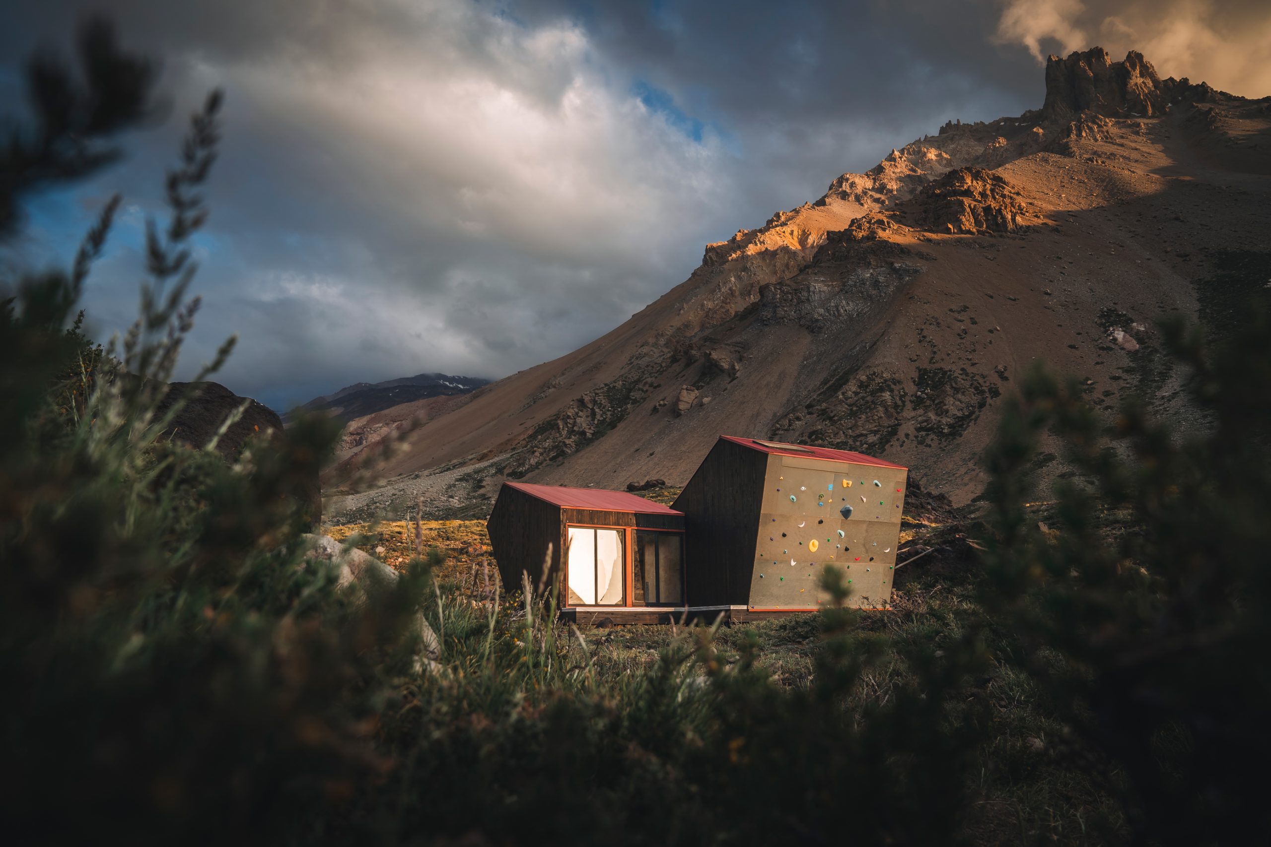 Fotografía de una estructura hecha de madera con ventana y techo rojo que funciona como refugio de montaña.