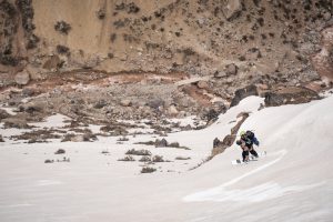 Fotografía de una persona realizando trekking en Chile caminando por una zona cubierta de nieve usando ropa abrigadora.